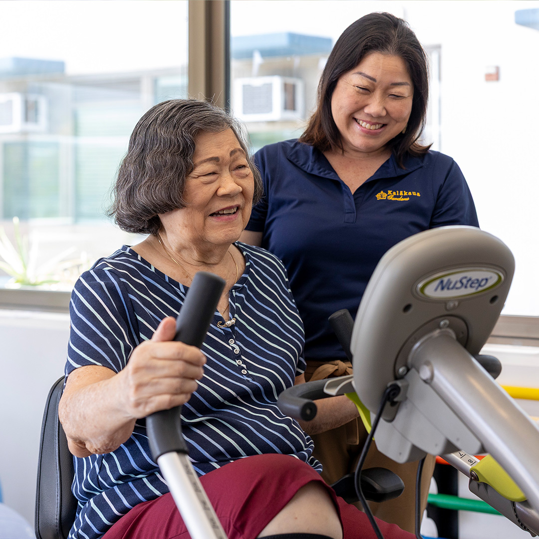 Kalakaua staff smiling and standing next to a client on a recumbent bicycle